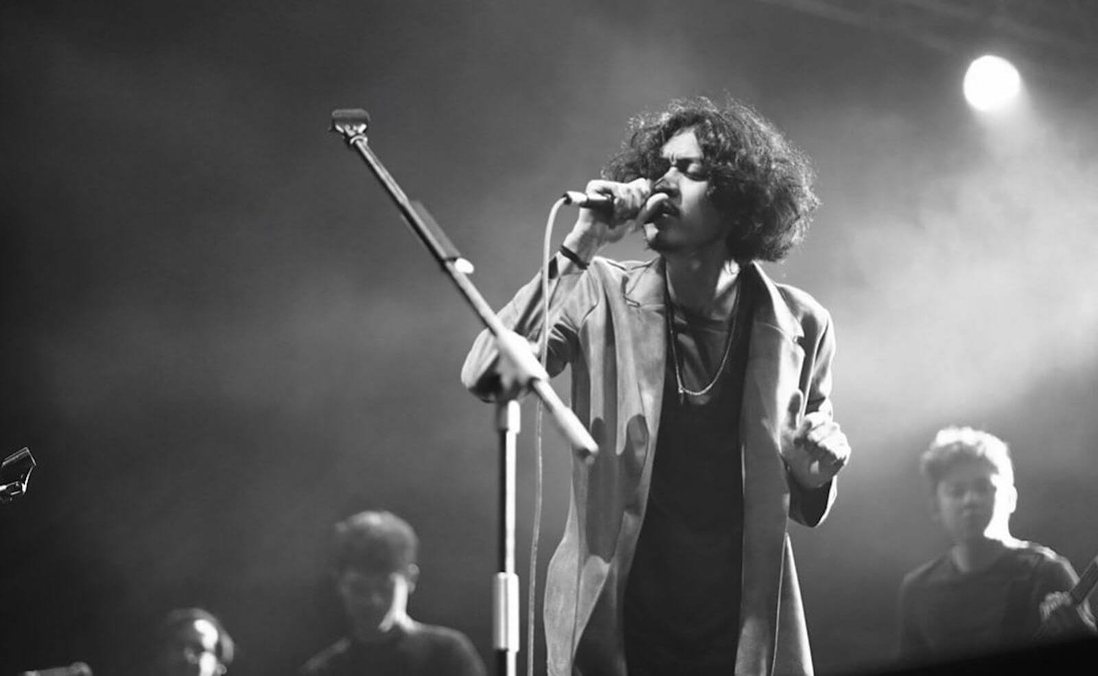 Pamungkas dengan blazer sedang bernyanyi di atas panggung